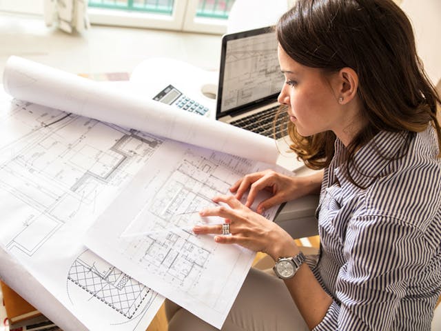 Architektin plant ein Haus mit Bauzeichnungen