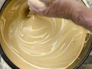 Farbe und Lack, Bild eines Mannes, der einen Farbeimer vor sich hat und die darin befindliche beige Farbe mit weiß abtönt und umrührt, Foto: iStock.com / MPKphoto Farbe und Lack, Bild eines Mannes, der einen Farbeimer vor sich hat und die darin befindliche beige Farbe mit weiß abtönt und umrührt, Foto: iStock.com / MPKphoto