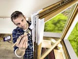 Holzfenster streichen, Foto von oben auf einen Mann, der sein Holzfenster weiß streicht, Foto: Hornbach
