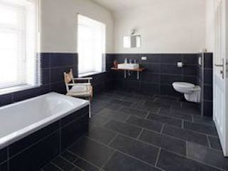 Natursteinboden, Bild eines Bades mit schwarzen Schieferfliesen auf Boden und der halben Wand, mit Badewanne, Waschbecken, Handtuchwärmer und Toilette, Foto: contrastwerkstatt / stock.adobe.com