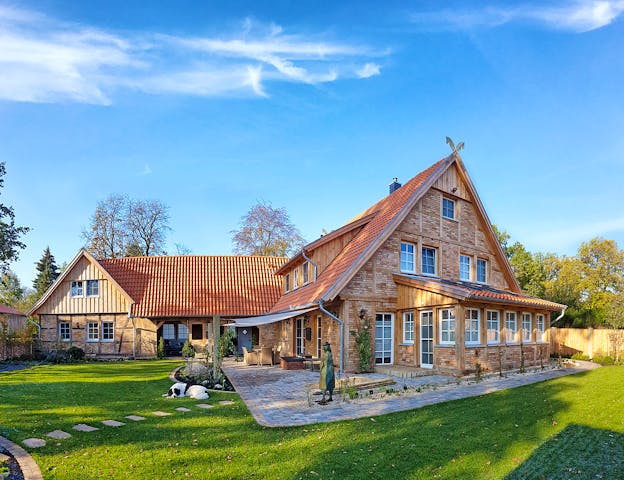 Modernes Landhaus mit Fachwerk, Backsteinen und Sprossenfenstern von Fuhrberger Zimmerei – besonders charmant sind hübsche Details wie die gekreuzten Pferdeköpfe als traditionelle Giebelzier