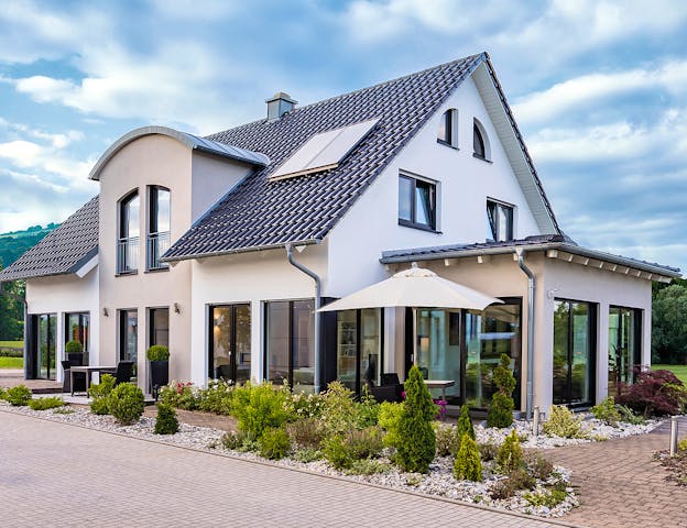 Fertighaus oder Massivhaus? Dem weiß verputzten Einfamilienhaus mit Satteldach, Erker und Wintergarten Variant 275 von Hanse Haussieht sieht man die Bauweise von außen nicht an.