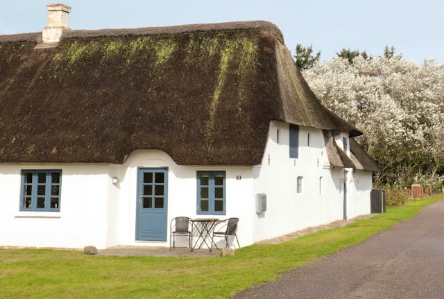 Traditionelles nordisches Haus mit Krüppelwalmdach und Reetdeckung