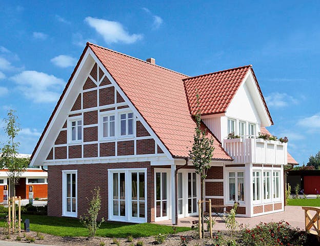 Modernes Landhaus mit Fachwerk, Klinker und Sprossenfenstern von Kampa – besonders charmant sind hübsche Details wie der weiße Holzbalkon auf dem Standerker.
