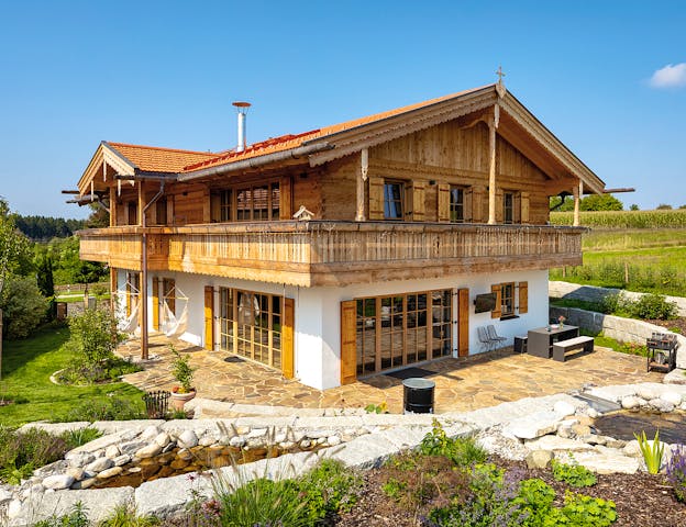Traditionelles bayerisches Holzhaus mit umlaufendem Holzbalkon und weiß verputztem Untergeschoss von Regnauer.